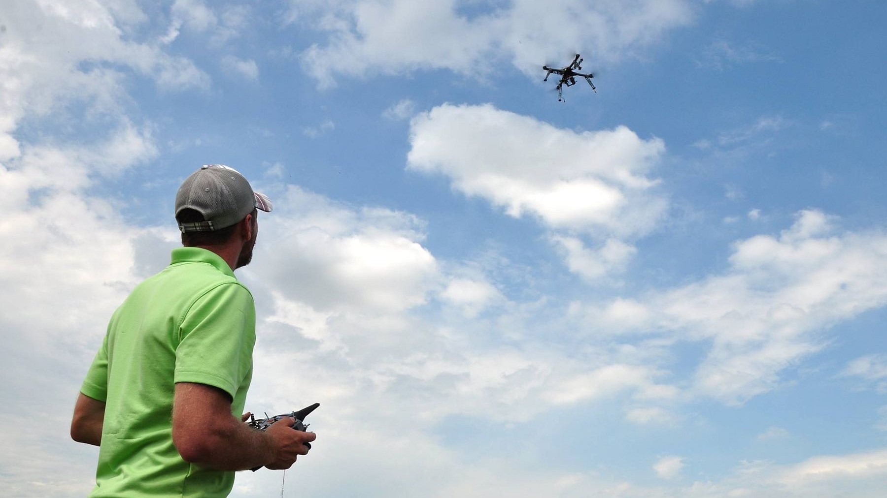 A photo of Tyler Nigon piloting a drone over a research field 