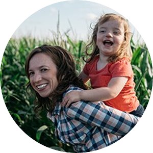 A photo of Nancy Bohl Bormann giving her daughter a piggy back ride in a corn field