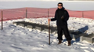 A photo of LAAS graduate student Luis Allen in a snowy field checking his manure fertilizer plots 